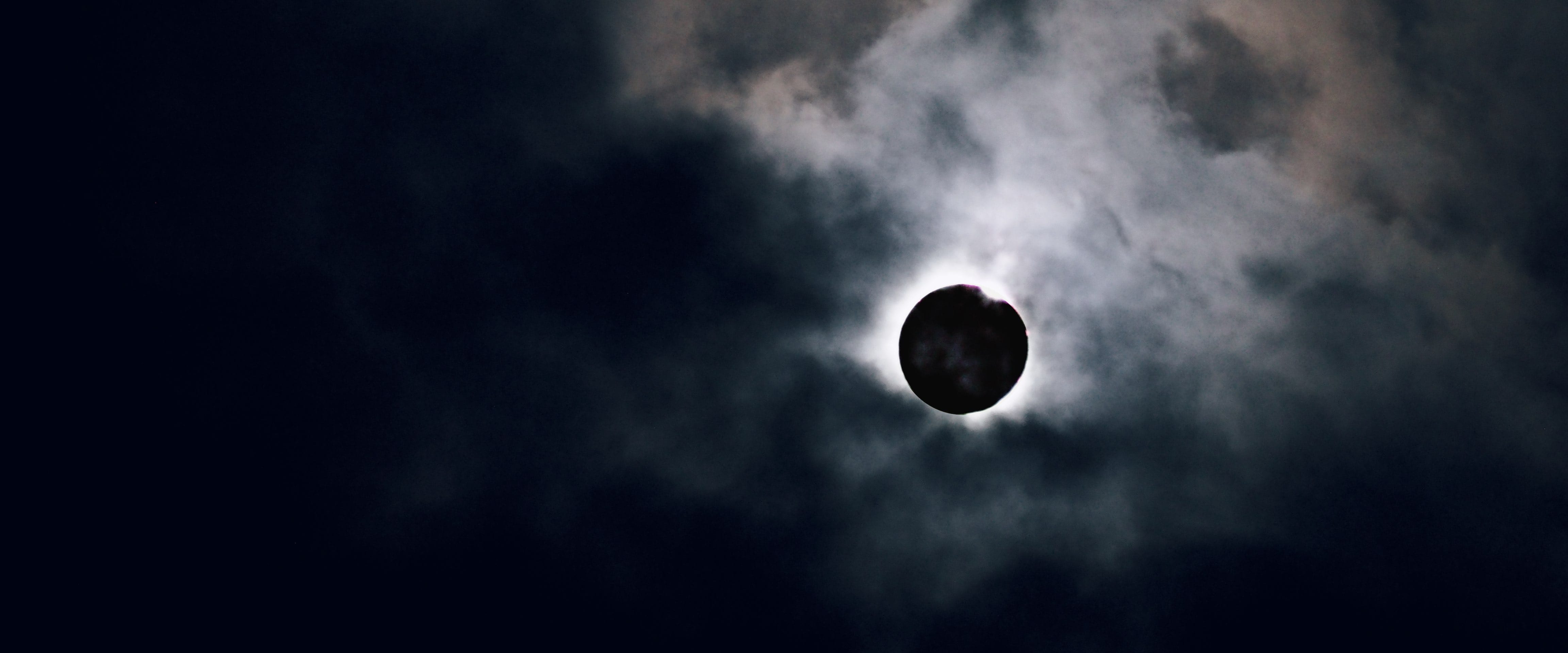 A solar eclipse behind broken clouds